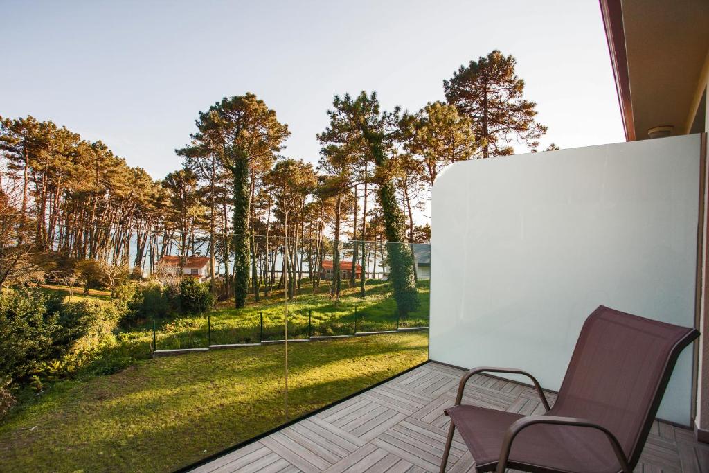 a balcony with two chairs and a view of a yard at Hotel Alén do Mar in Finisterre