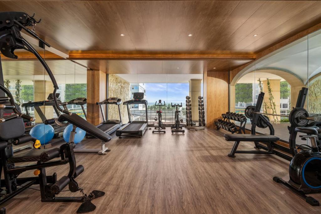 A spacious mirrored gym with cardio equipment, free weights, and a street-facing window.