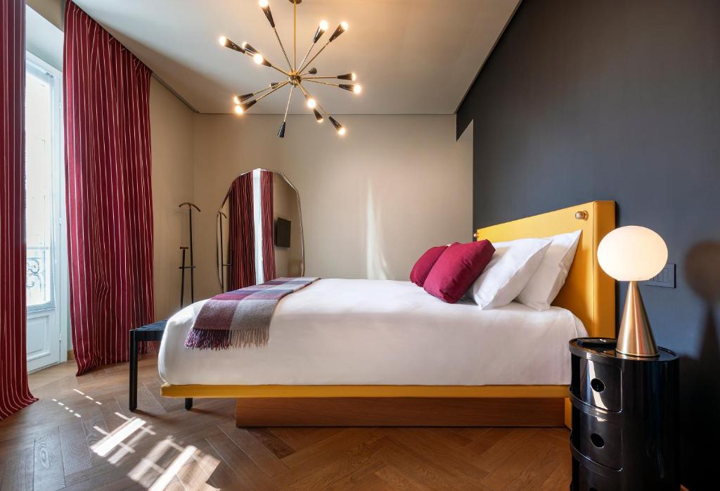 a bedroom with a large bed and a chandelier at DOMYA - Manzoni 25 in Milan