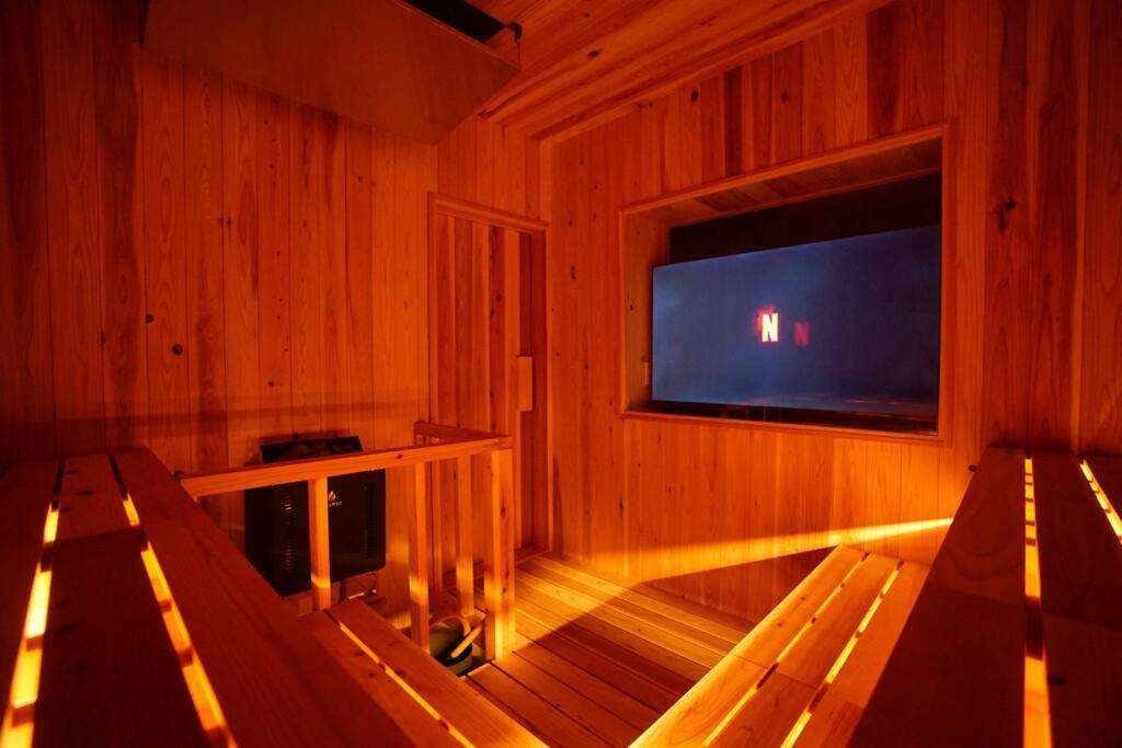 a wooden room with a tv and two benches at Sauna Private Villa AO in Takashima