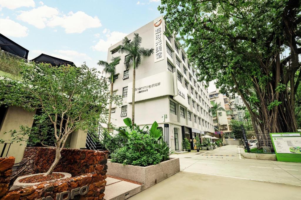 a building on the side of a street with trees at 超时光酒店 广州天河岗顶地铁站店 in Guangzhou