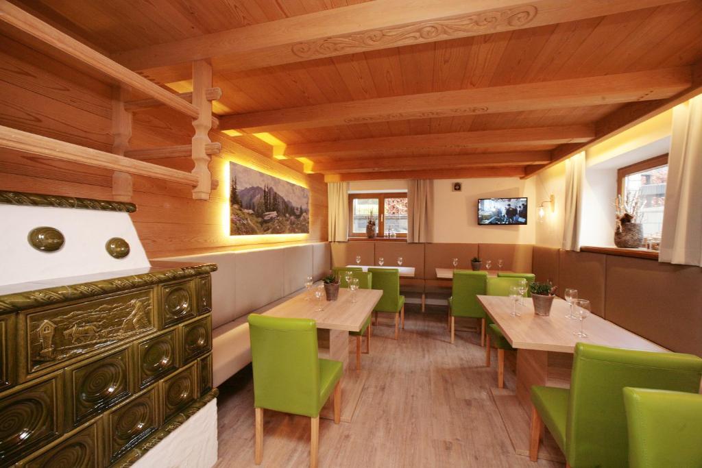 a restaurant with wooden ceilings and green tables and chairs at Premium Chalet Andrea in Leogang