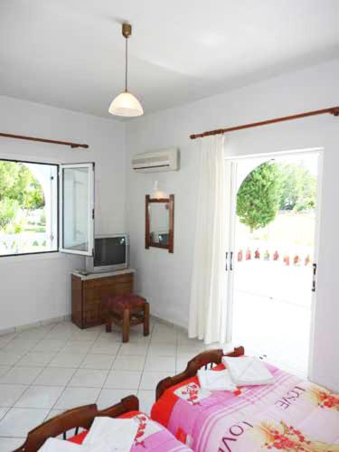 a bedroom with two beds and a tv and a window at Lazanis Studios Apartments in Laganas