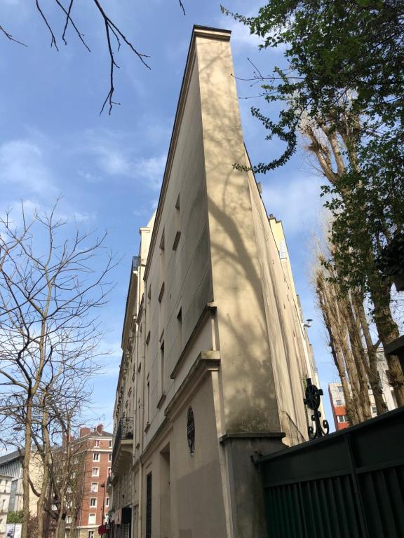 un grand bâtiment dans une rue de la ville bordée d'arbres dans l'établissement Urban retreat in Paris, à Paris
