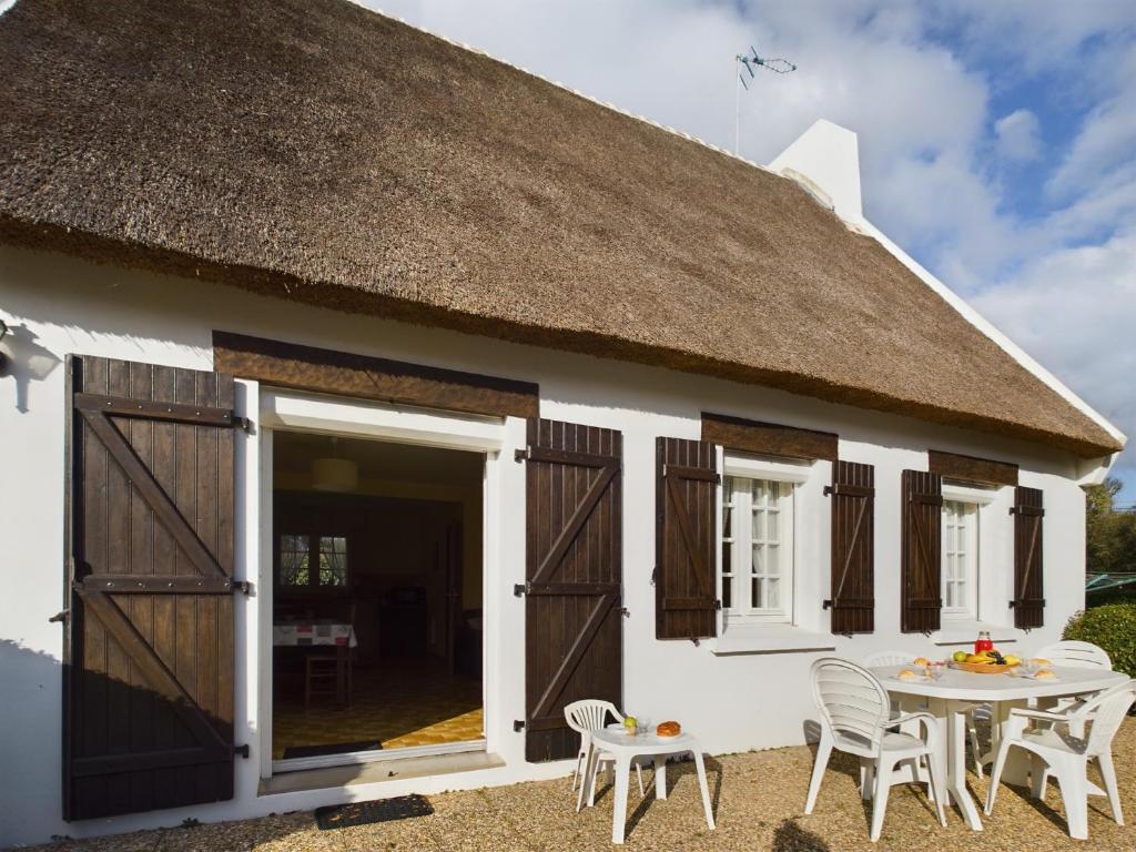 Ce cottage dispose d'un toit de chaume, d'une table et de chaises. dans l'établissement -HANSEL- Belle Chaumiere a Kerascoet, à Névez
