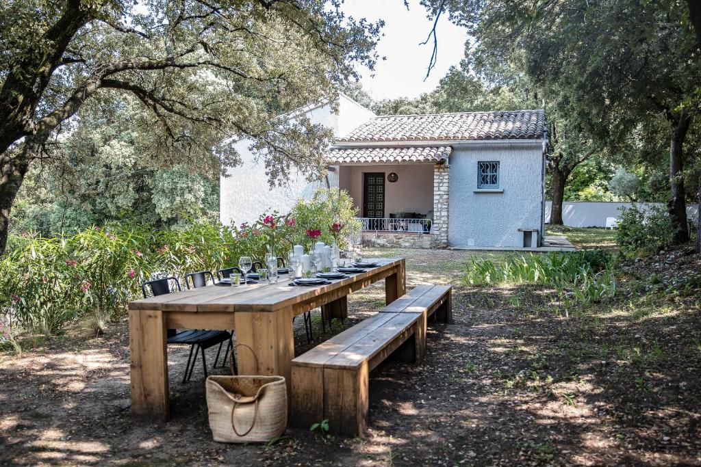 - une table et des chaises en bois dans une cour avec une maison dans l'établissement Villa Lys, Charme en Luxe, à La Roque-sur-Cèze