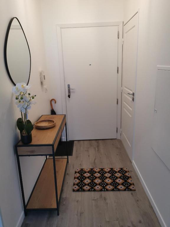 un couloir avec une table, un miroir et une porte dans l'établissement Appartement Cosy à Clichy, avec parking ,proche Paris!, à Clichy