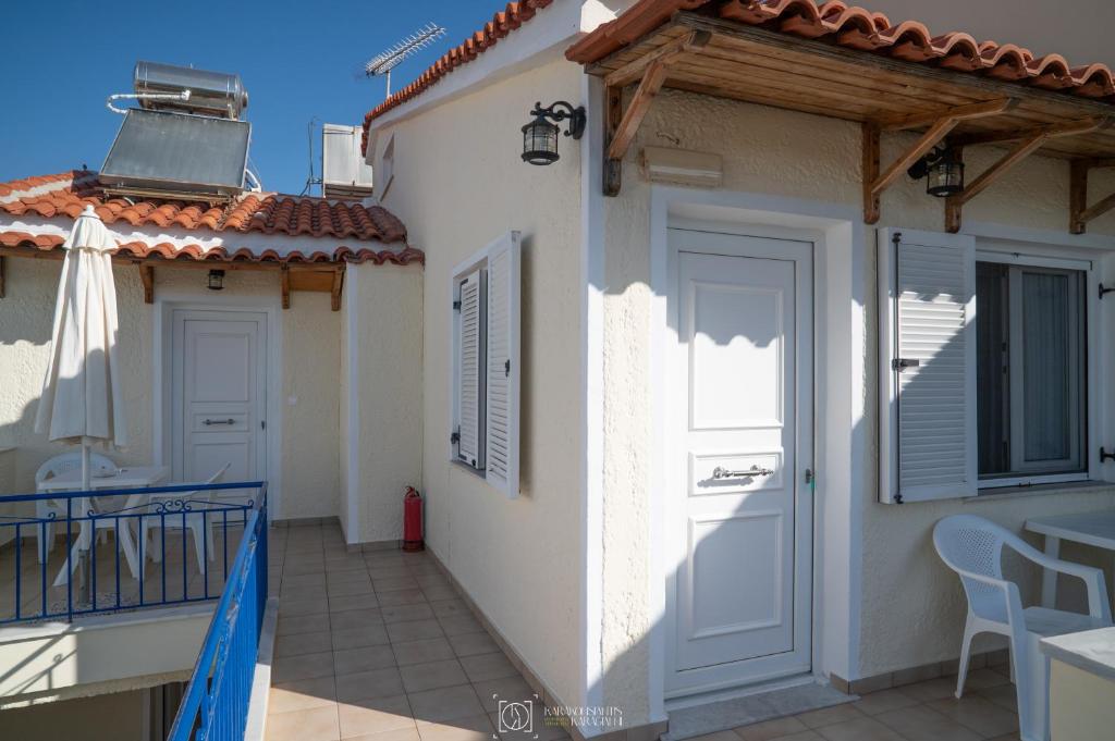 a white house with a balcony and a door at Elli Studios & Apartments in Marathokampos