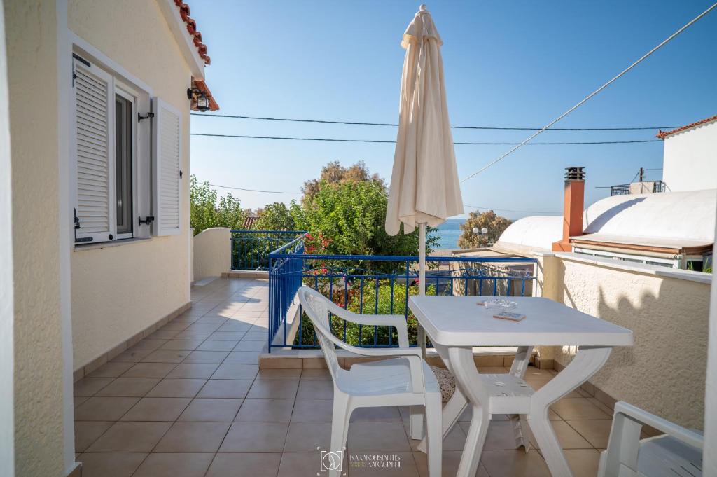 a white table and chairs on a balcony with an umbrella at Elli Studios & Apartments in Marathokampos
