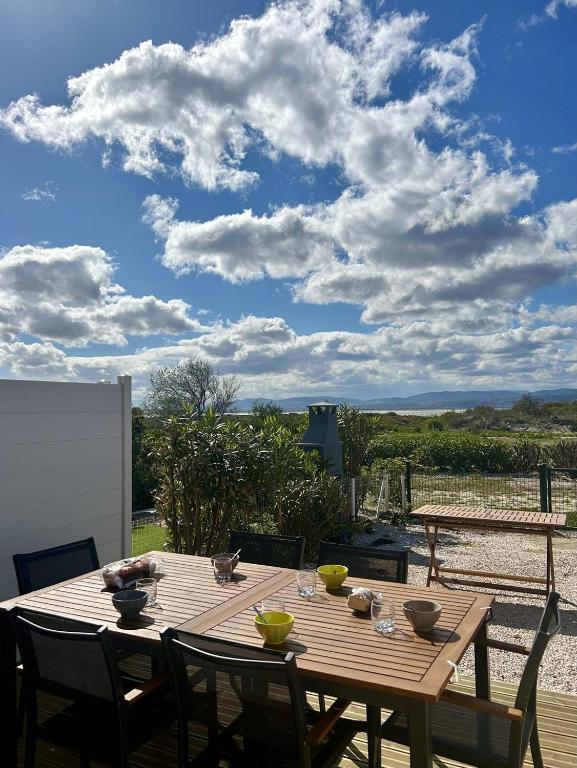 - une table en bois avec des chaises sur la terrasse dans l'établissement Charmante maison agréable pour les vacances 4BCAP64, au Barcarès