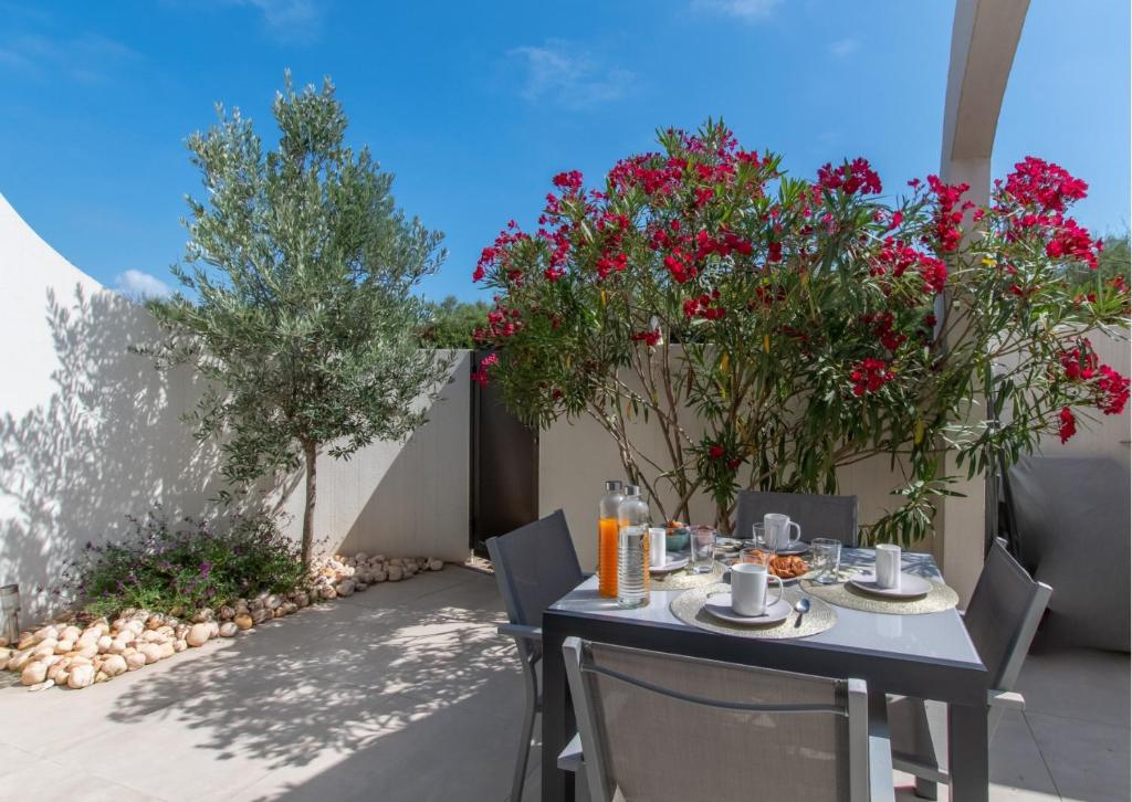 - une table et des chaises sur une terrasse fleurie dans l'établissement Maison de plage Les Grenadines 50M de la MER Clim, à La Grande Motte