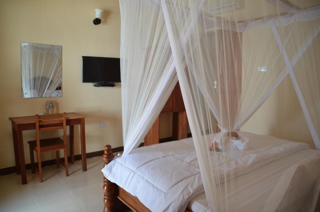 a bedroom with a canopy bed with a desk at Sea View Beach Hotel in Zanzibar City