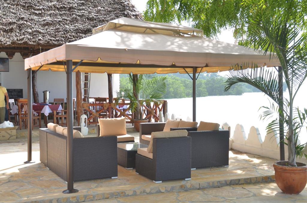 a pavilion with chairs and an umbrella on a patio at Sea View Beach Hotel in Zanzibar City