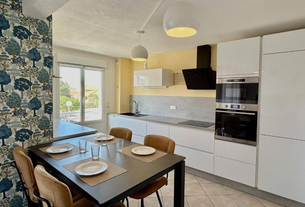 une cuisine avec une table et des chaises dans une pièce dans l'établissement SUPERBE appartement T3 - piscine- Terrasse- Parking- 900 m plage 6PIN2102, au Barcarès