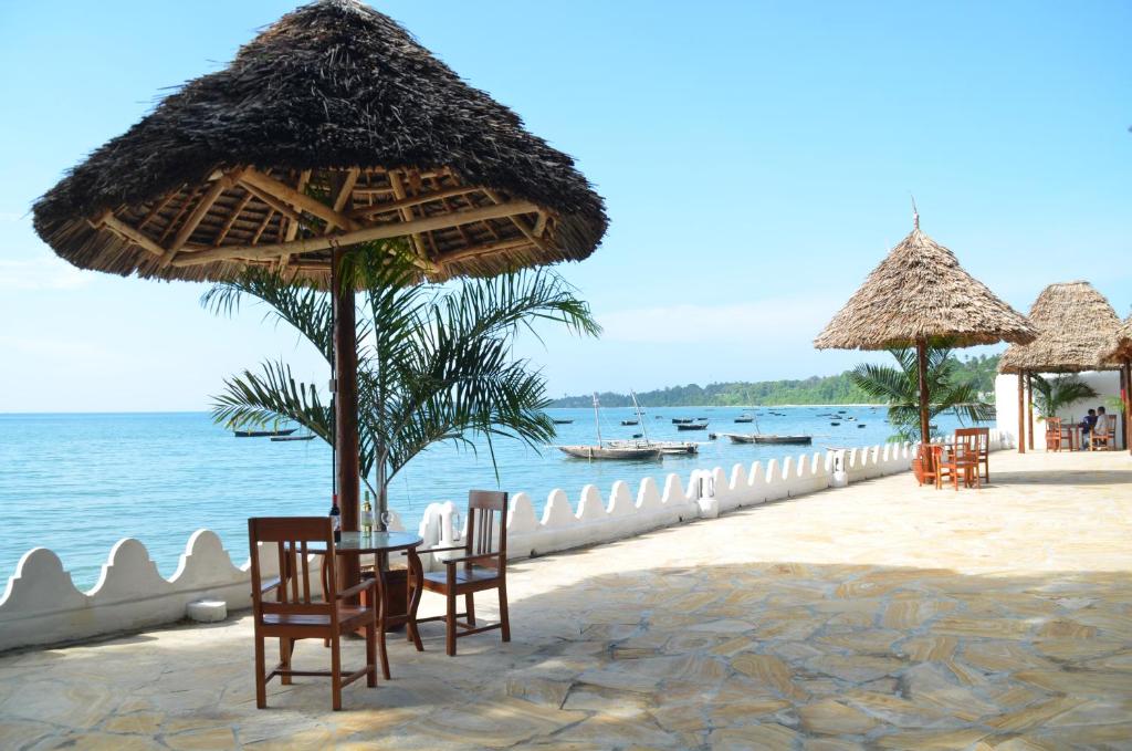 a beach with chairs and umbrellas and the ocean at Sea View Beach Hotel in Zanzibar City