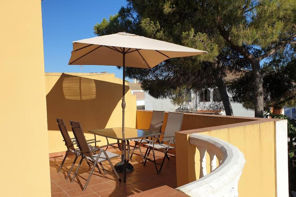 un tavolo e sedie con un ombrellone in un patio di Islantilla Urbasur 1 dormitorio y terraza a Islantilla
