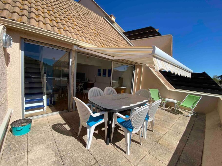 un patio avec une table et des chaises sur un patio dans l'établissement Marseillan plage 5pers proche plage climatisé, à Marseillan