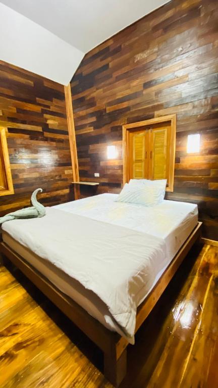 a bed in a room with a wooden wall at Cocoa Home in Ban Ko Phrao