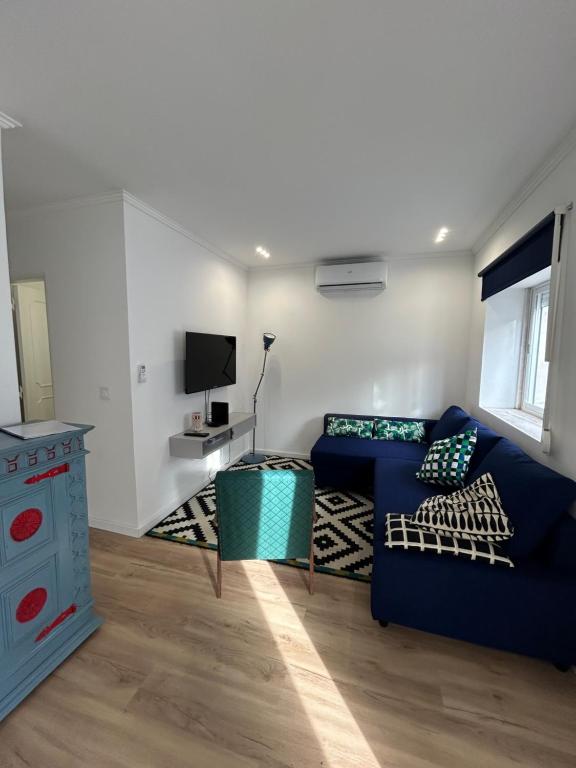 a living room with a blue couch and a tv at Casinha da Portela in Sintra