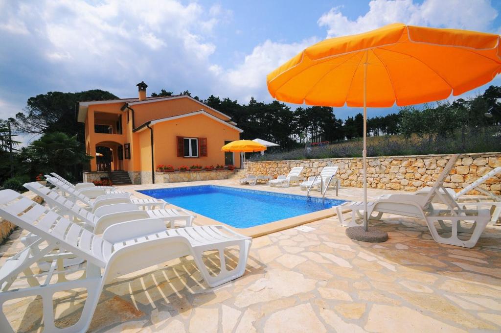 a pool with white chairs and an orange umbrella at Holiday Apartment Ori in Nedeščina
