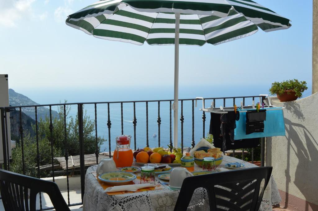 un tavolo con cibo e ombrellone su un balcone di B&B La Selva Santa a Positano