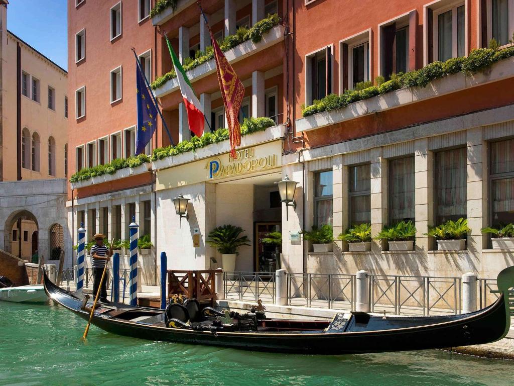 a gondola in the water in front of a building at Papadopoli Hotel Venezia - MGallery Collection in Venice