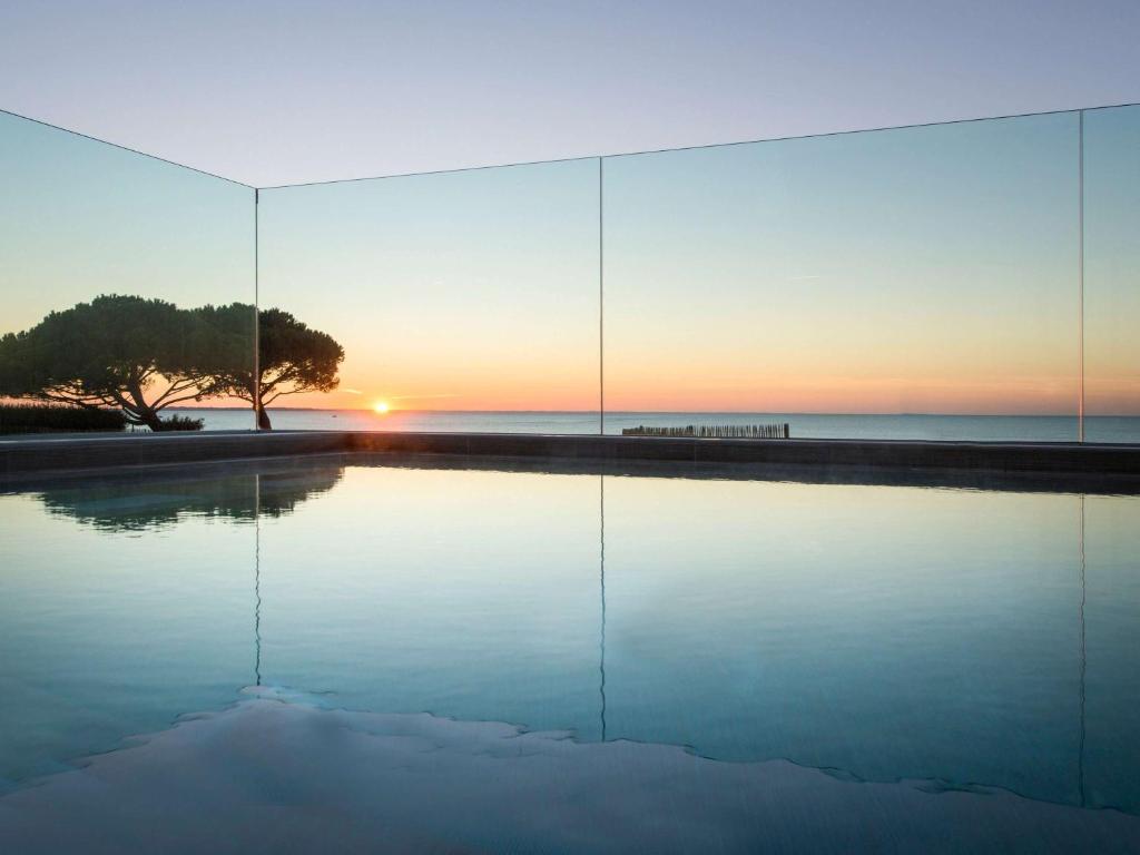 une piscine réfléchissante face à l'océan au coucher du soleil dans l'établissement La Grande Terrasse Hotel & Spa La Rochelle - MGallery Collection, à Châtelaillon-Plage