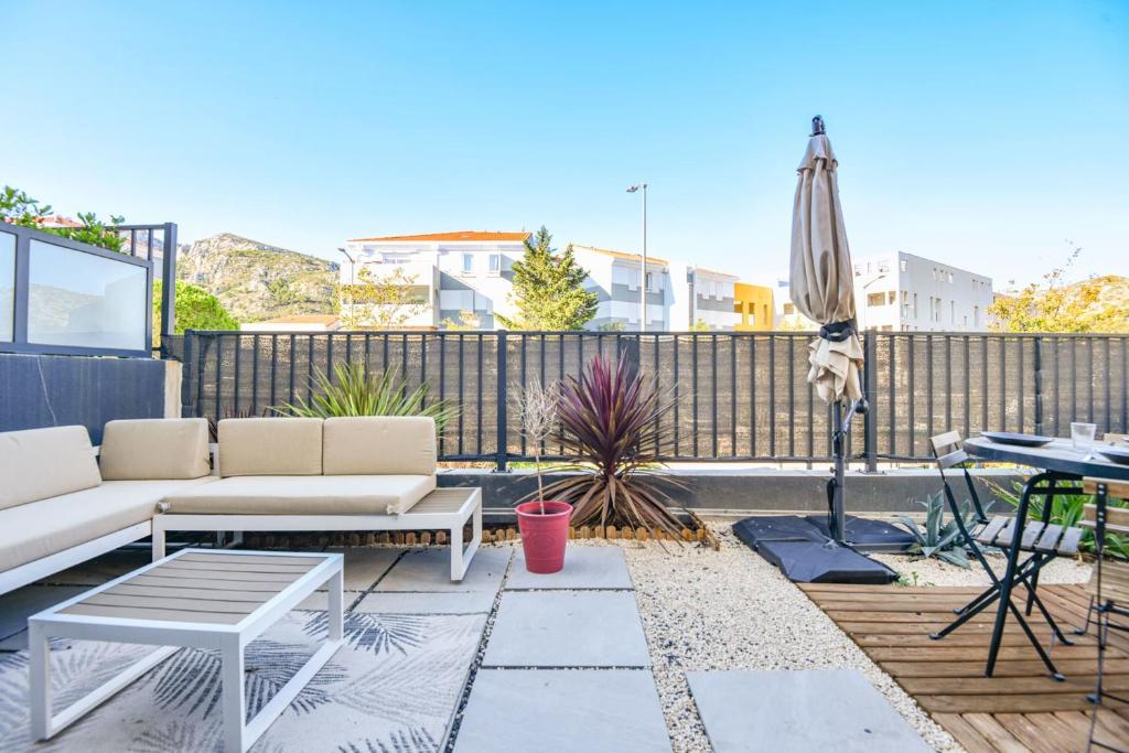 une terrasse avec un canapé, un parasol et une table dans l'établissement Le Vallon - Bel appart 2 ch avec terrasse, à Marseille