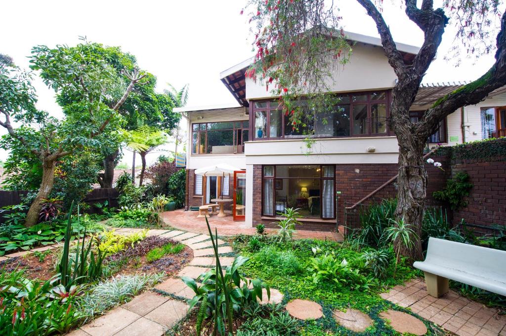 una casa con un banco en un jardín en Oliveroom Self Catering and B&B en Durban