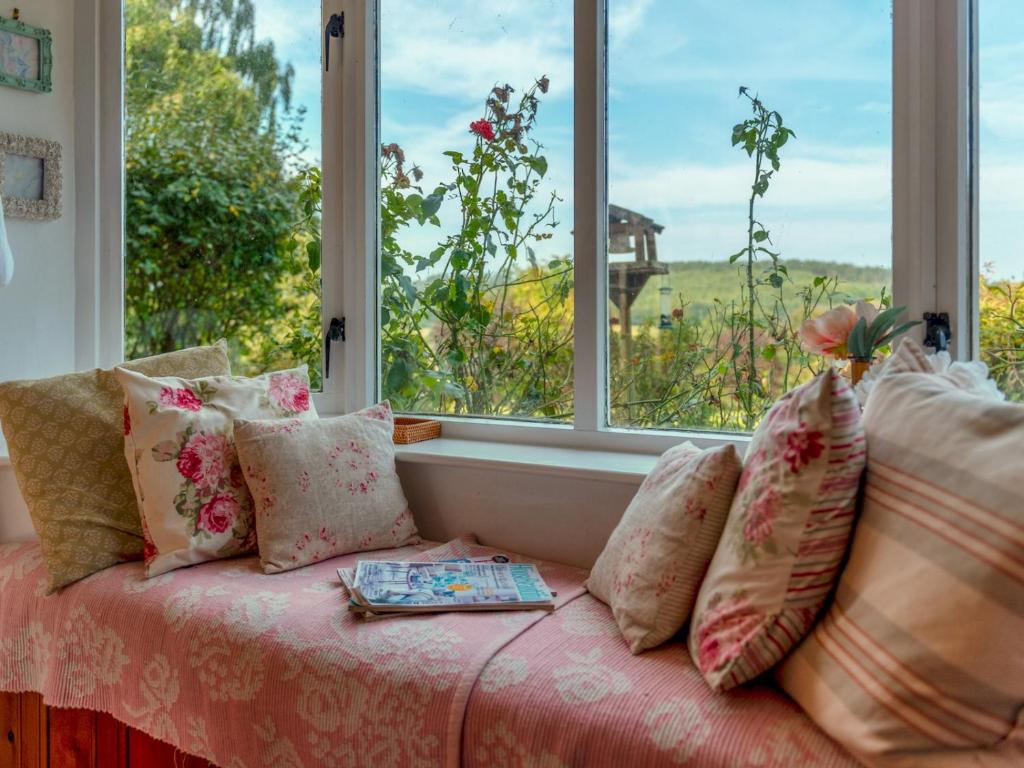 a couch in front of a window with a book on it at Charming 17th Cent Secluded Country Cottage Garden - Pass the Keys in Eccleshall
