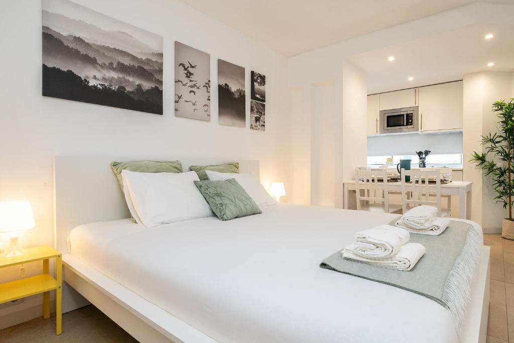 a bedroom with a large white bed and a kitchen at Apartamento Golden Naimara in Cabanas de Tavira
