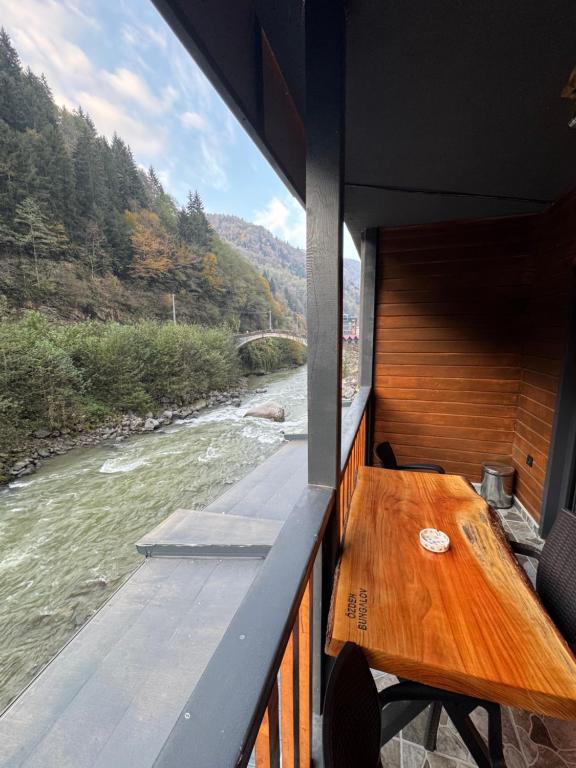una mesa de madera en la cubierta de un barco en un río en Özden Bungalow, en Çamlıhemşin
