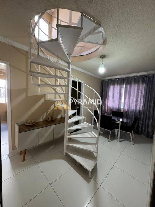 una scala a chiocciola in metallo in un soggiorno con una scrivania di Duplex Cobertura Premium a Feira de Santana