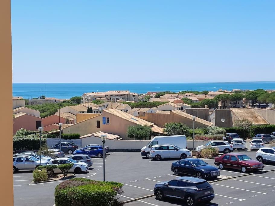 a parking lot with cars parked in front of the ocean at Appartement Saint Pierre la Mer 5 personnes, vue sur la mer, piscine, parking, tennis C164 in Saint Pierre La Mer