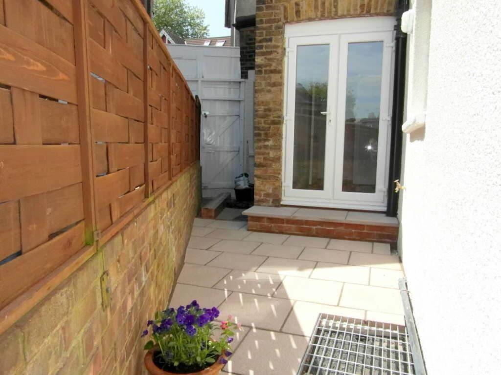 a patio with a brick wall and a window and flowers at Central Stay in Watford
