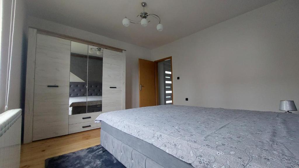 a white bedroom with a bed and a dresser at Kuća za odmor Pale - Jahorina in Pale