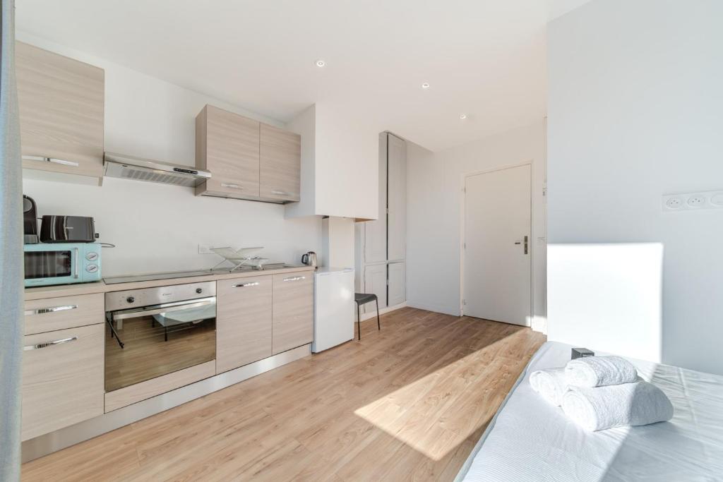una cocina con armarios blancos y una cama en una habitación en Maison Fontanières Studio Laurent 2 persons, en La Mulatière