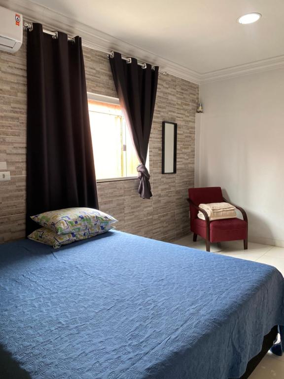 una camera da letto con un letto blu e una finestra di Belíssima Suíte a Trindade