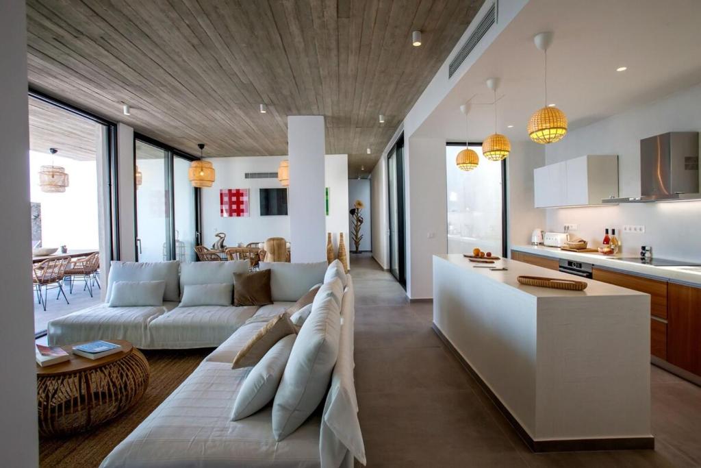 a living room with a white couch and a kitchen at Magic Cave Villa in Tinos in Agios Sostis