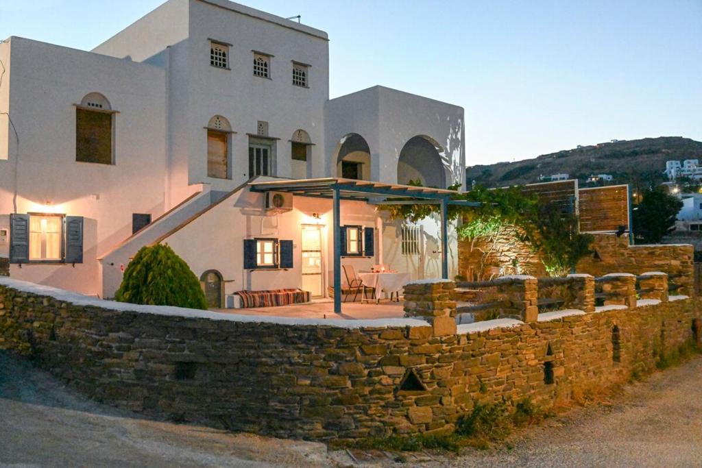 a house with a stone wall in front of it at La Luna in Agia Barbara Tinos in Agios Sostis