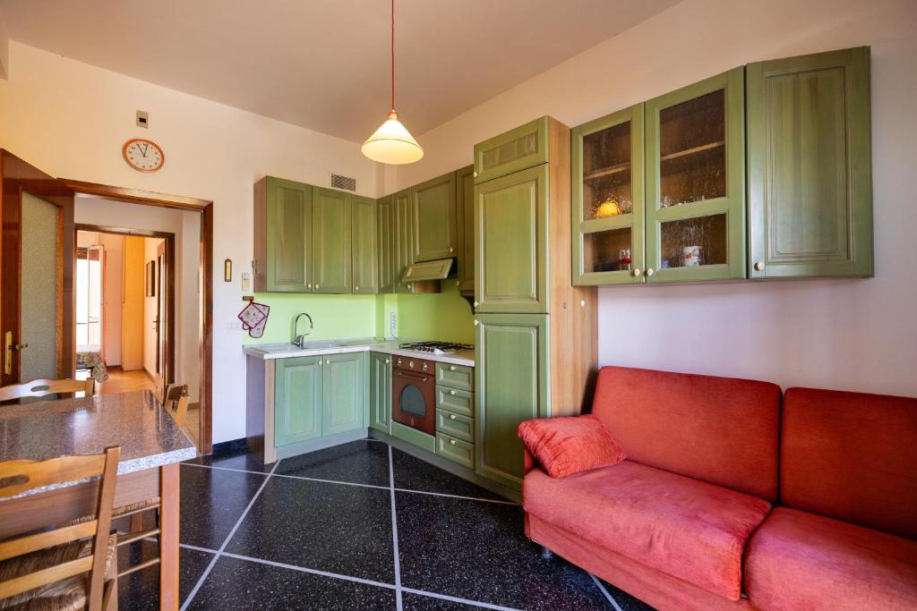 a kitchen with green cabinets and a red couch at Ba Cio Del Mare by Holiday World in Cogoleto