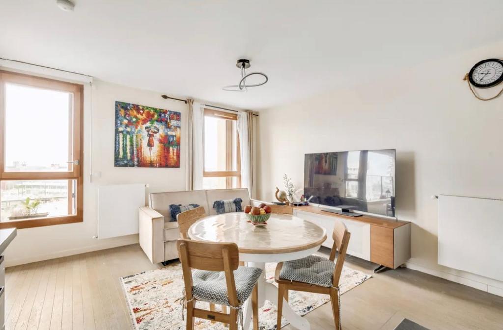 a living room with a table and chairs and a tv at Chic Appartement Sacré Cœur of Paris with Parking in Paris
