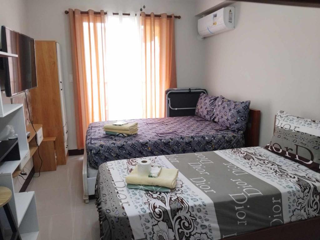 um pequeno quarto com 2 camas e um sofá em Yuki's Place 1516 em Lapu Lapu City