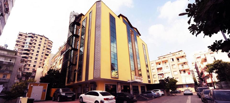 a large yellow building with cars parked in a city at Şehri Saray Otel in Seyhan