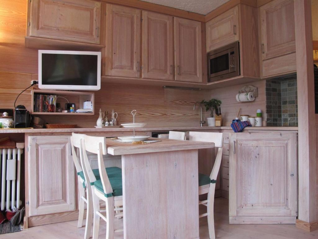 kuchnia z drewnianymi szafkami i blatem z krzesłami w obiekcie Profumo di Legno a Cielo Alto La Coquille w mieście Breuil-Cervinia
