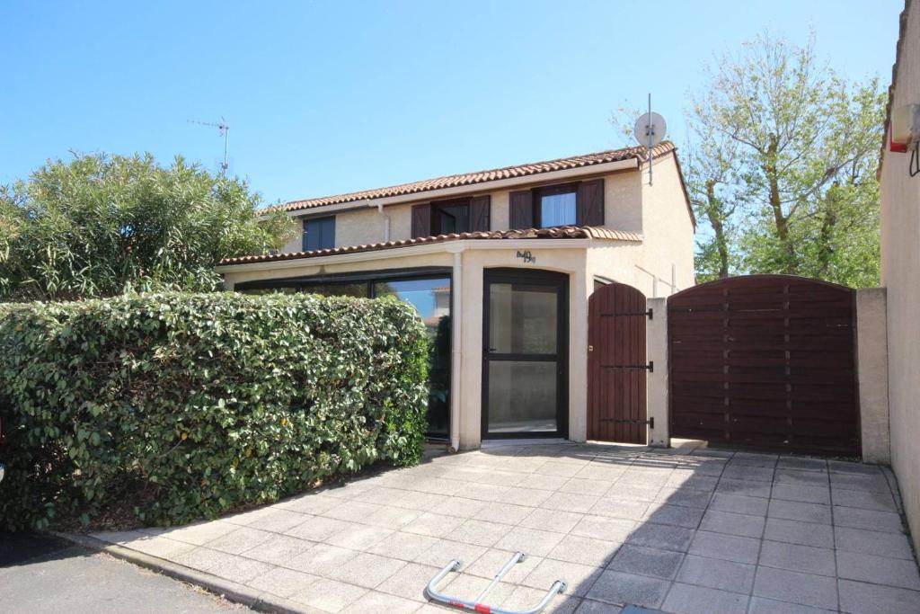 une maison avec une clôture et un garage dans l'établissement Belle villa de vacances climatisee, tout confort, residence TAMARIS, accès payant aux piscines animation, wifi, 2 chambres, 5 couchages PORTIRAGNES PLAGE LRTAMB19, à Portiragnes