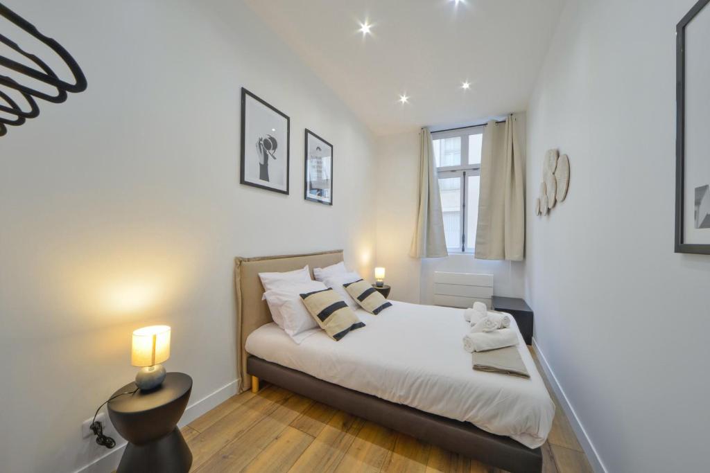 une chambre avec un lit avec des draps blancs et des oreillers dans l'établissement OIQIA • Échappée Belle, à Bourges