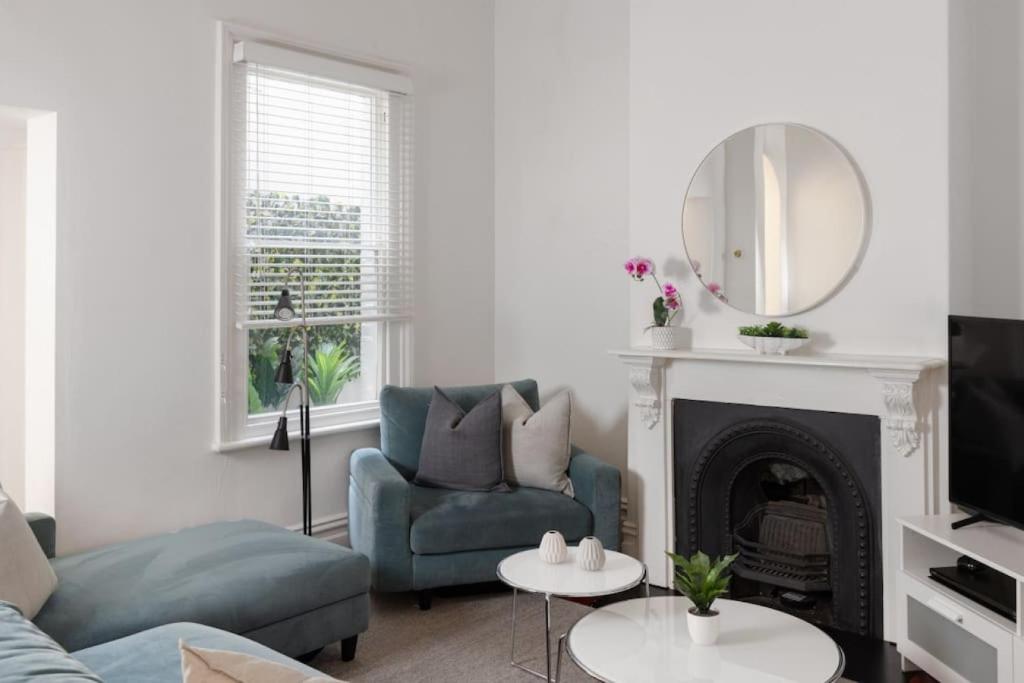 a living room with a couch and a mirror at Luxury On Lygon, Victorian Terrace in Melbourne