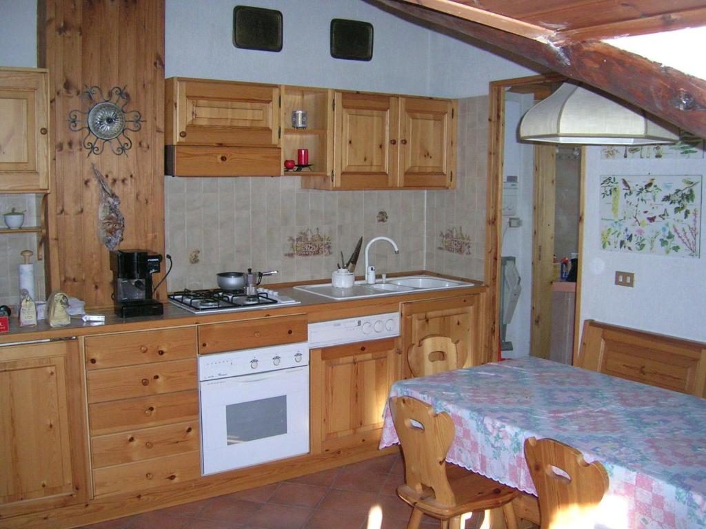 a kitchen with wooden cabinets and a table with a sink at Mansarda Jouvenceaux in Sauze dʼOulx