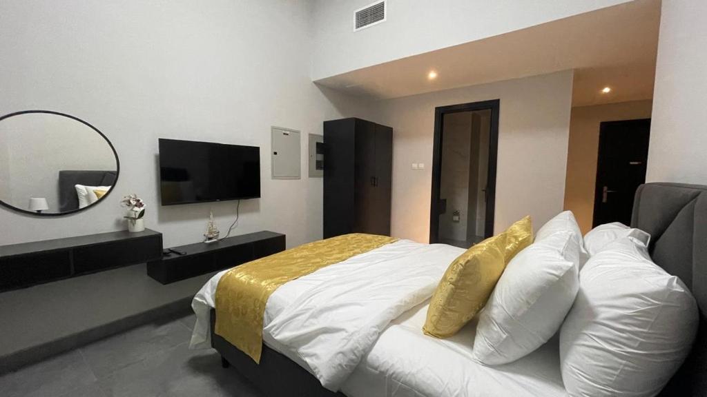 ein Schlafzimmer mit einem Bett mit einem Spiegel und einem TV in der Unterkunft Ista Vacation Homes LLC in Dubai